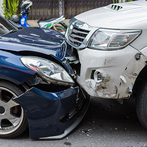 A frontal car crash between a dark blue and a white car.